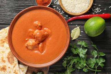 Delicious butter chicken served on wooden table, flat lay. Traditional indian Murgh Makhani