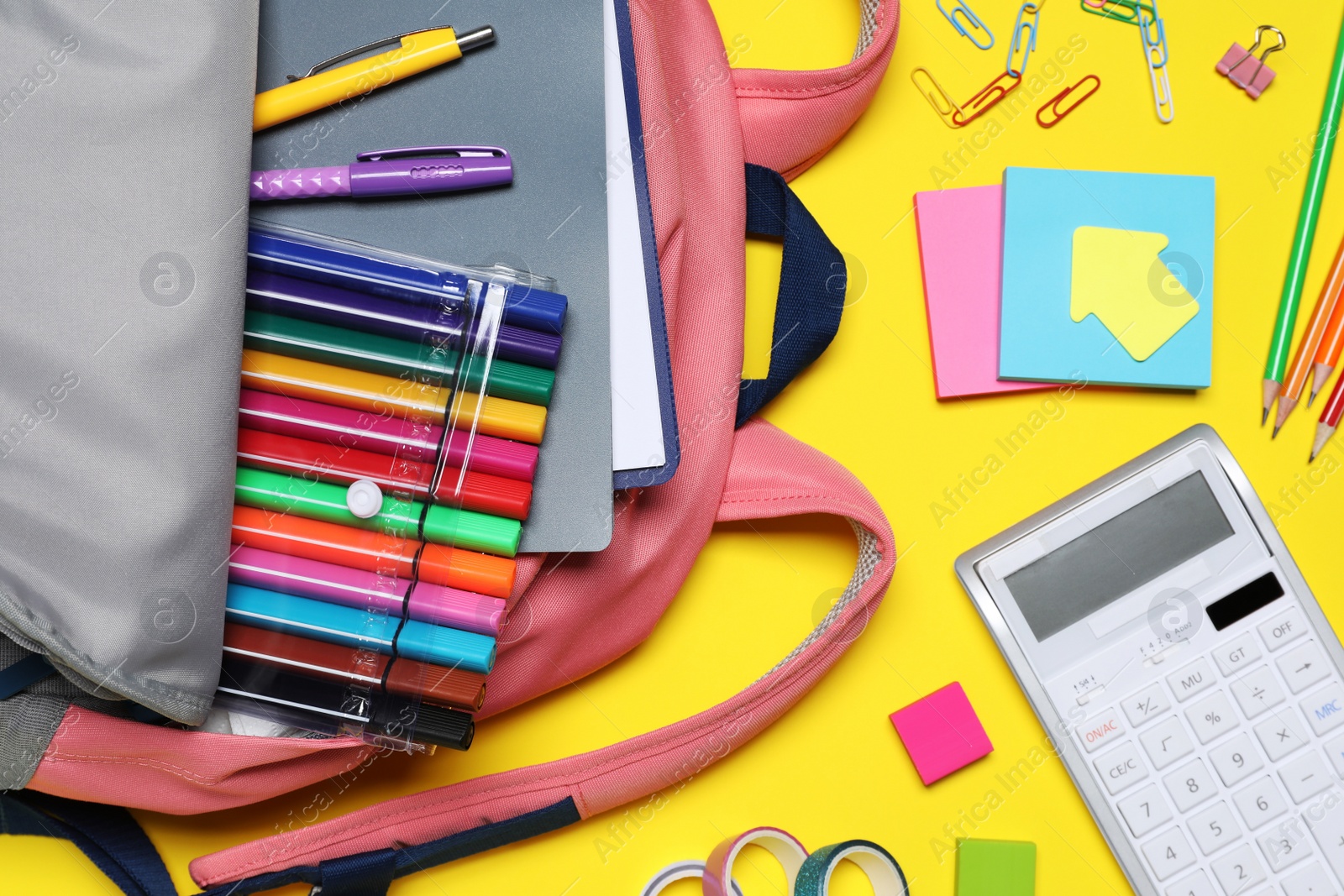 Photo of Flat lay composition with backpack and school stationery on yellow background