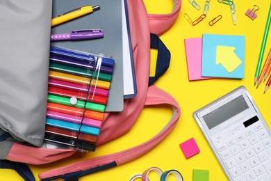 Photo of Flat lay composition with backpack and school stationery on yellow background
