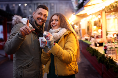 Happy couple with mulled wine at winter fair