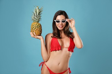 Photo of Beautiful woman in stylish bikini with pineapple on blue background