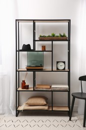 Photo of Stylish turntable with vinyl record on shelving unit indoors