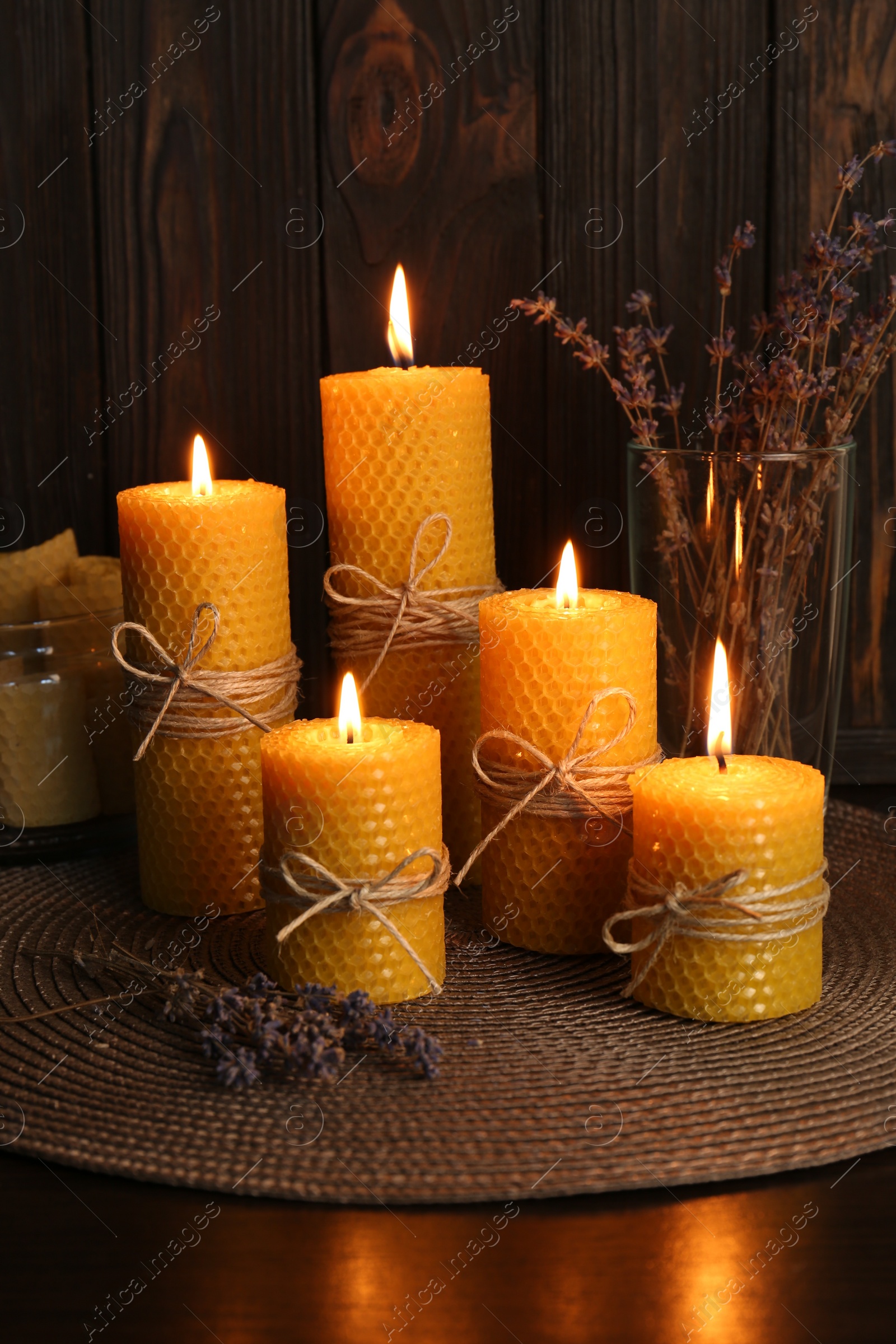 Photo of Beautiful burning beeswax candles and dried lavender flowers on table