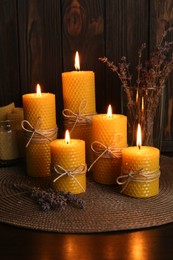 Beautiful burning beeswax candles and dried lavender flowers on table