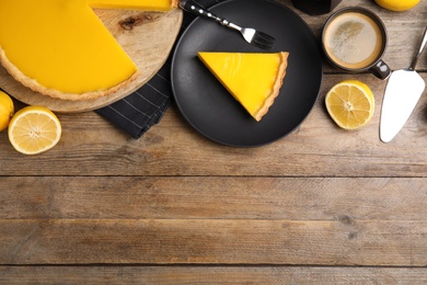 Photo of Delicious homemade lemon pie, fruits and coffee on wooden table, flat lay. Space for text