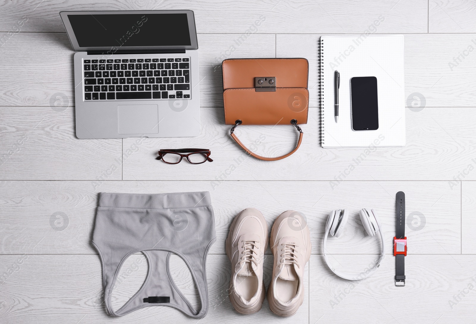 Photo of Flat lay composition with business supplies and sport equipment on white wooden floor. Concept of balance between work and life