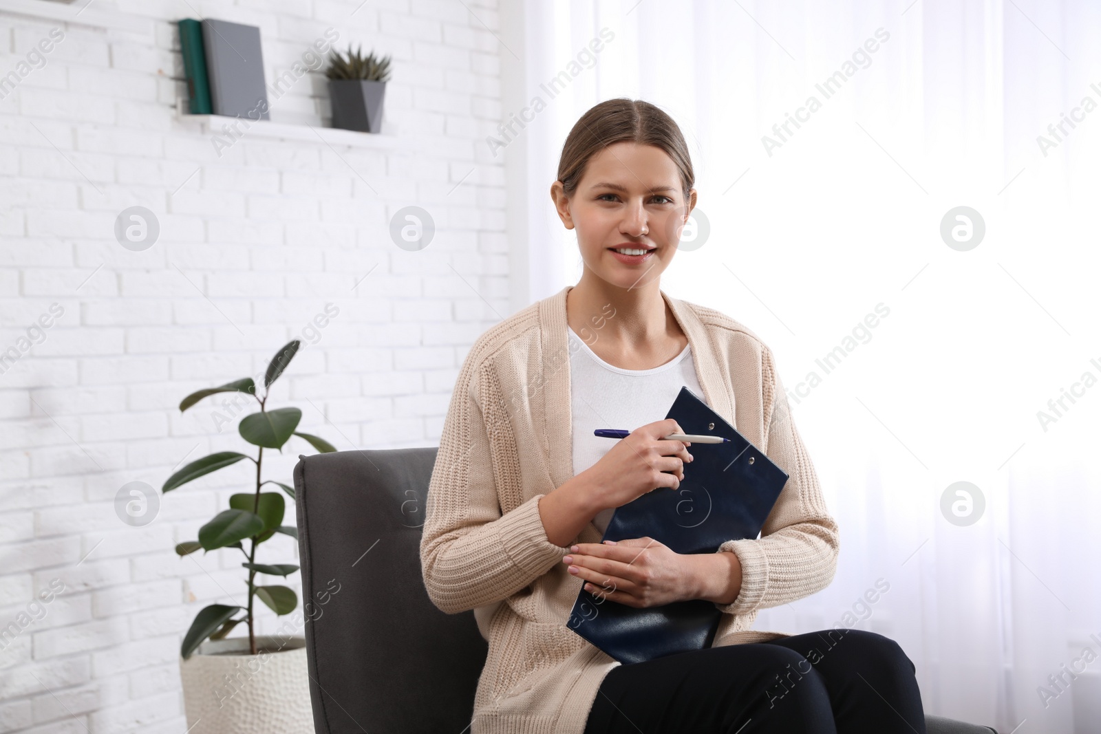 Photo of Professional psychotherapist with clipboard in modern office