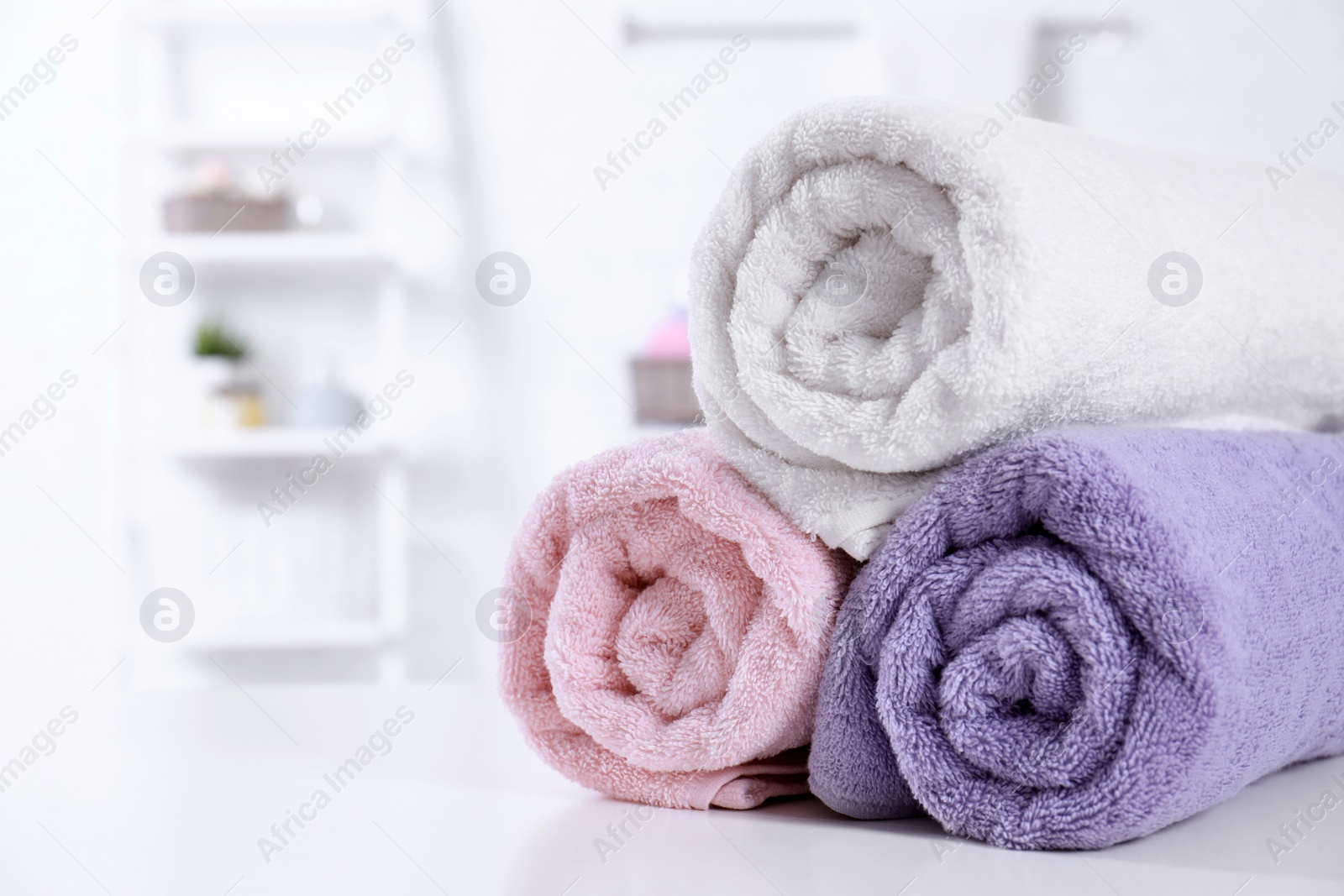 Photo of Rolled tidy towels on table in bathroom. Space for text