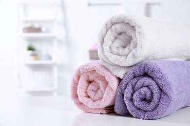 Rolled tidy towels on table in bathroom. Space for text