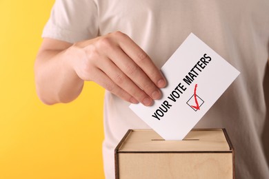 Image of Man putting paper with text Your Vote Matters and tick into ballot box on yellow background