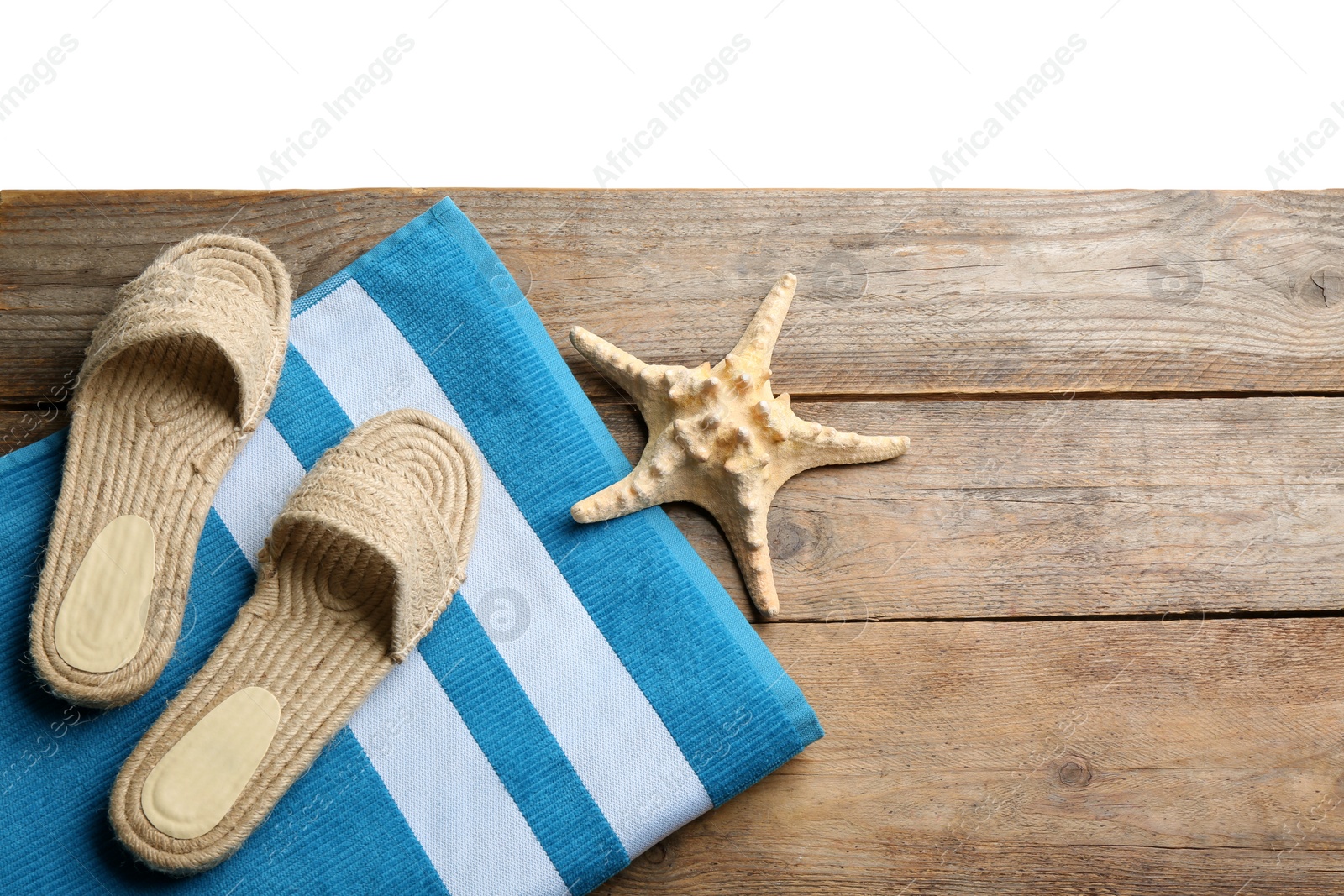 Photo of Shoes, towel and starfish on wooden table. Beach accessories