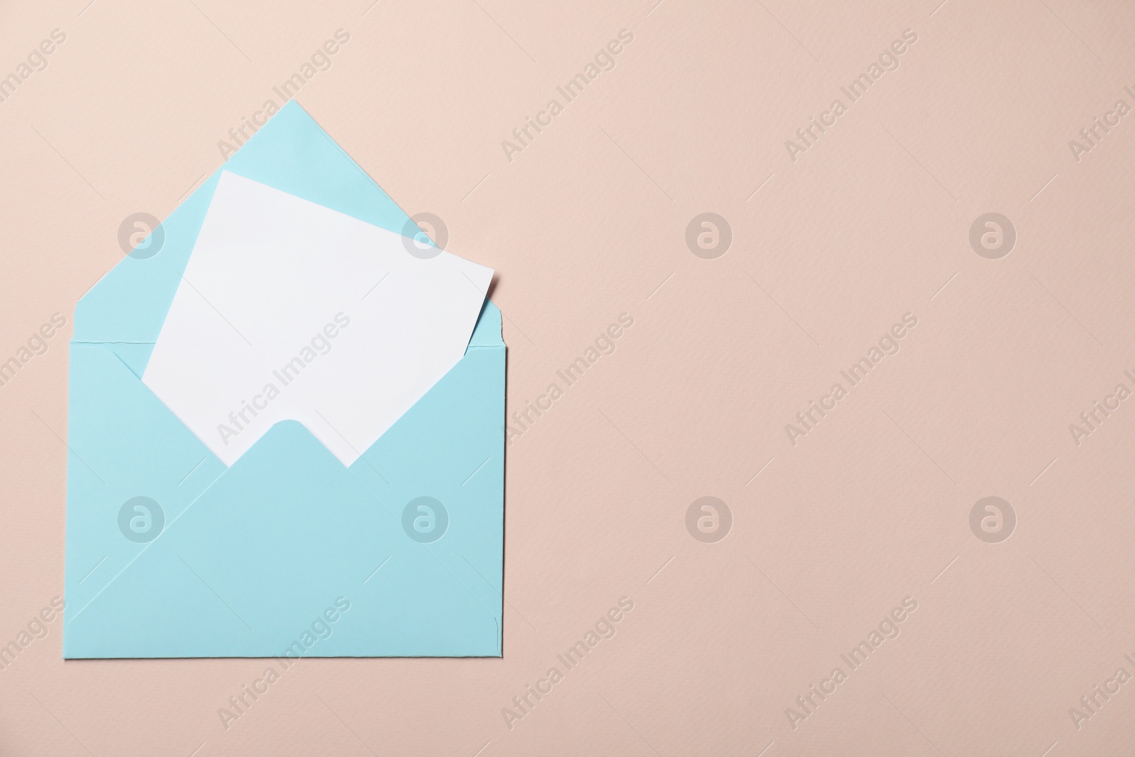 Photo of Letter envelope with card on beige background, top view. Space for text