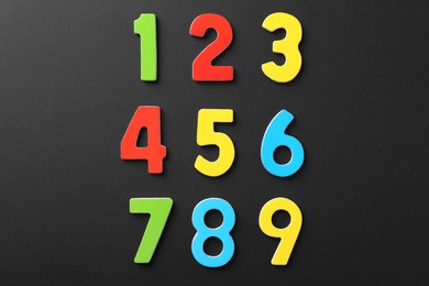 Photo of Colorful numbers on black background, flat lay