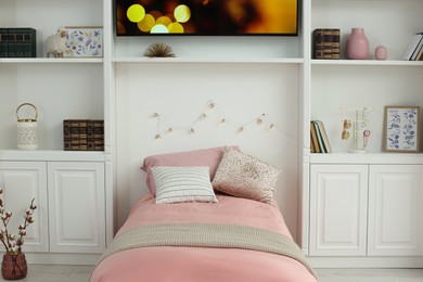 Photo of Stylish teenager's room interior with comfortable bed, shelves and TV set