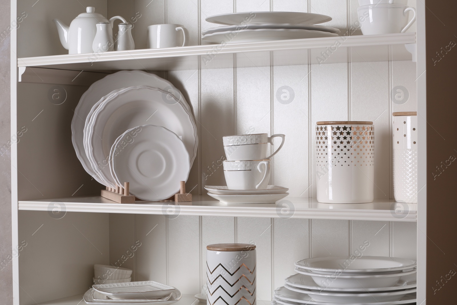 Photo of Stylish storage stand with different ceramic dishware at home