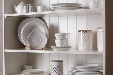 Stylish storage stand with different ceramic dishware at home