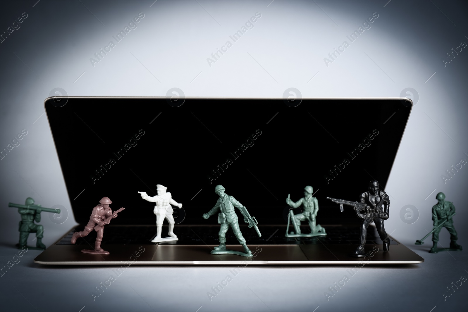 Photo of Hybrid warfare concept, online information battle. Laptop and toy soldiers on light grey background