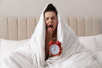 Photo of Overslept woman with alarm clock in bed. Being late concept