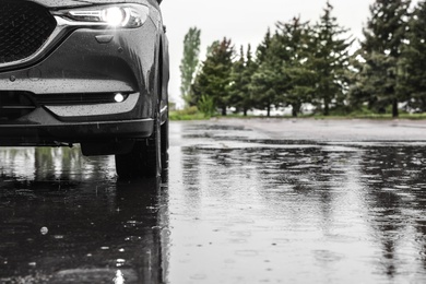 Photo of Modern car parked outdoors on rainy day