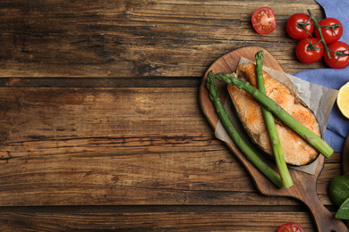 Tasty salmon steak served with asparagus on wooden table, flat lay. Space for text