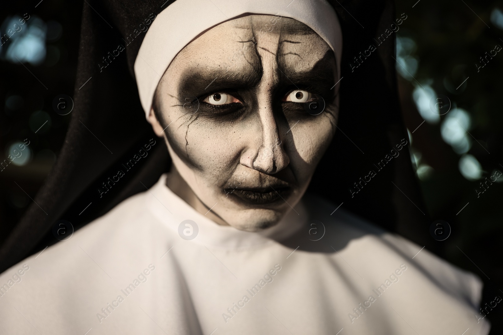 Photo of Portrait of scary devilish nun outdoors, closeup. Halloween party look