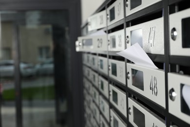 Photo of New mailboxes with keyholes, numbers and receipts near entrance in post office, closeup