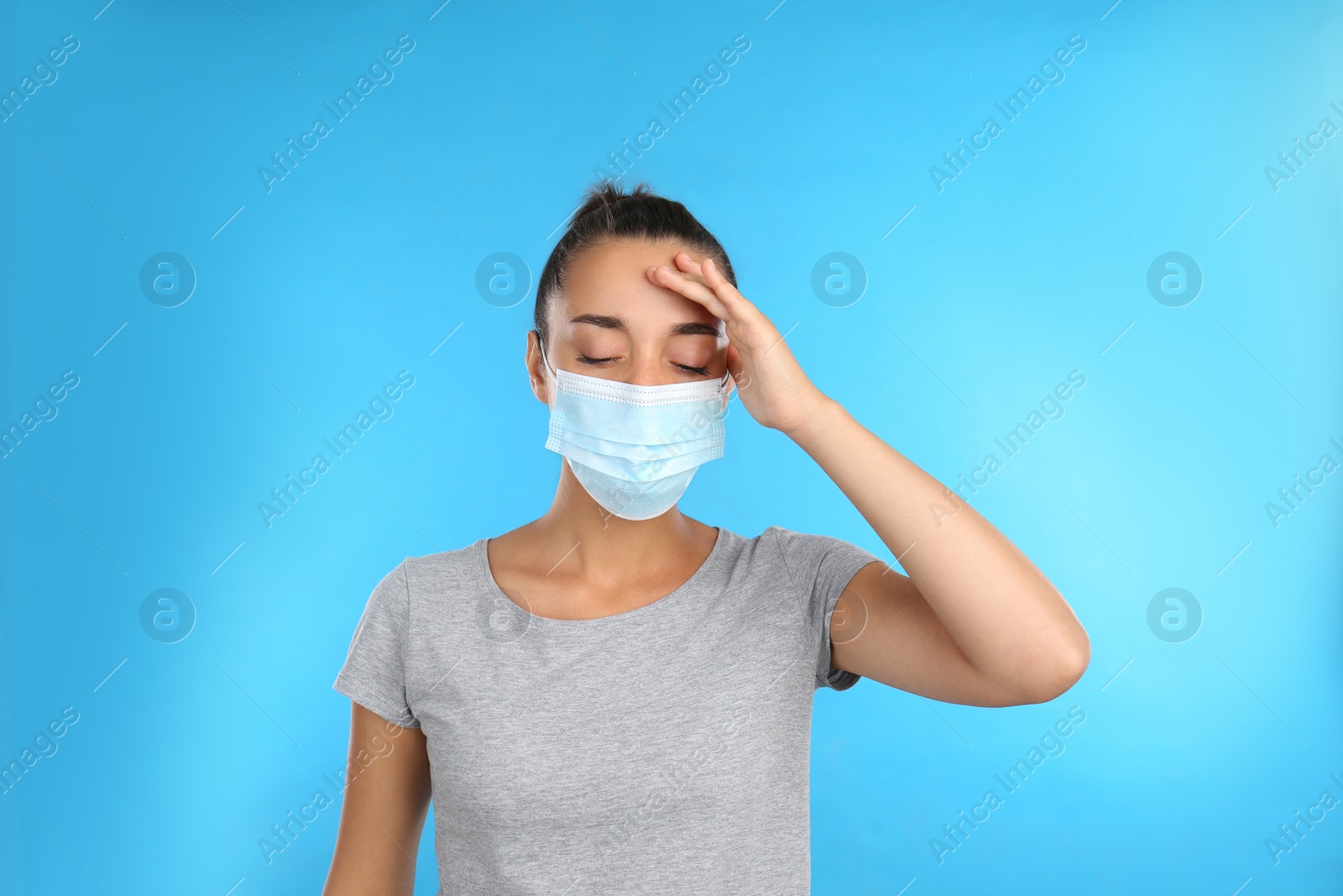 Photo of Stressed woman in protective mask on light blue background. Mental health problems during COVID-19 pandemic