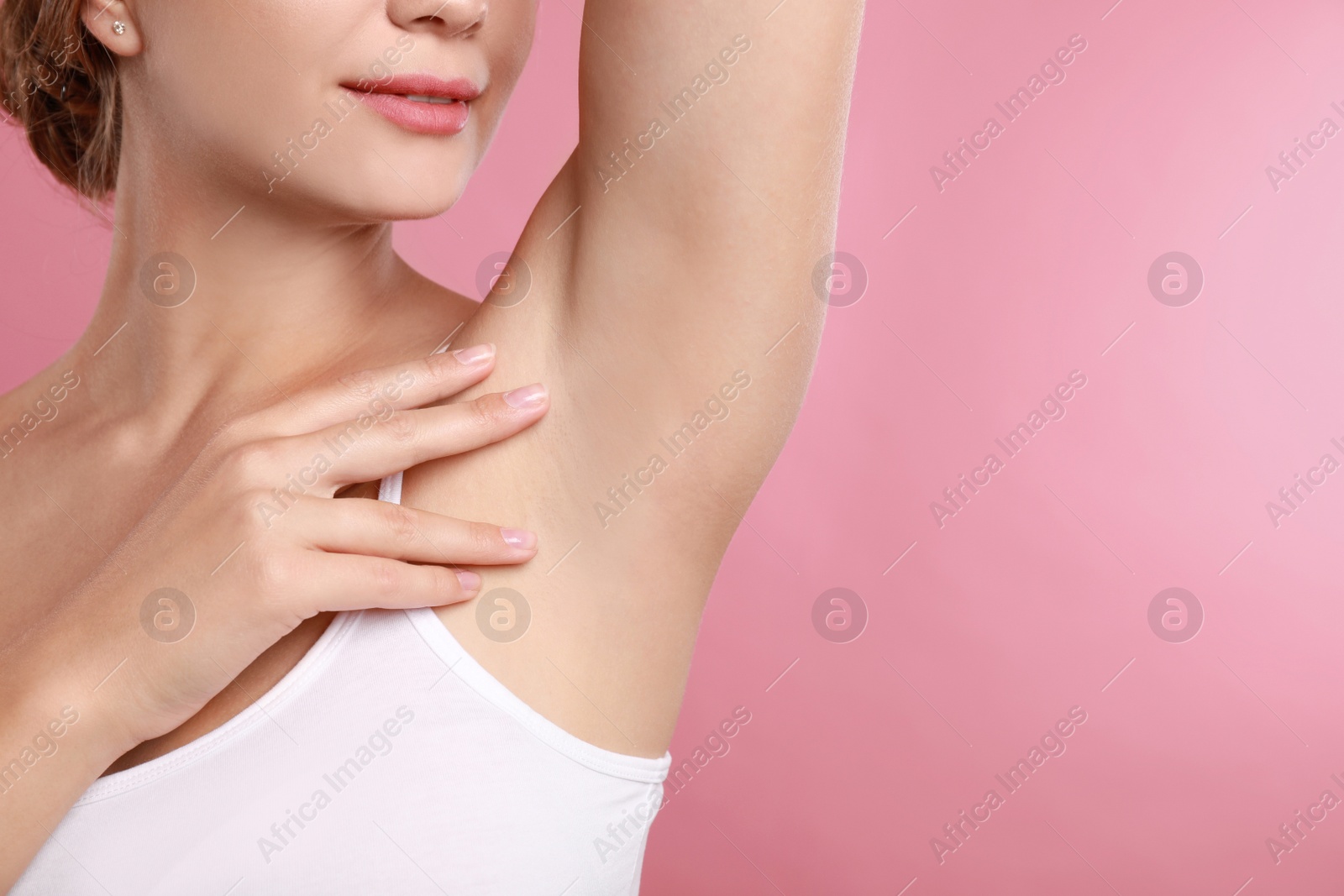 Photo of Young woman with smooth clean armpit on pink background, space for text. Using deodorant