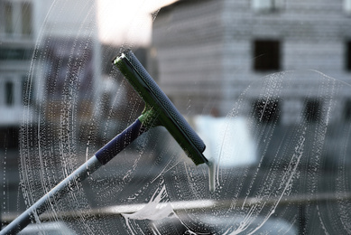 Cleaning window with squeegee indoors. Household chores