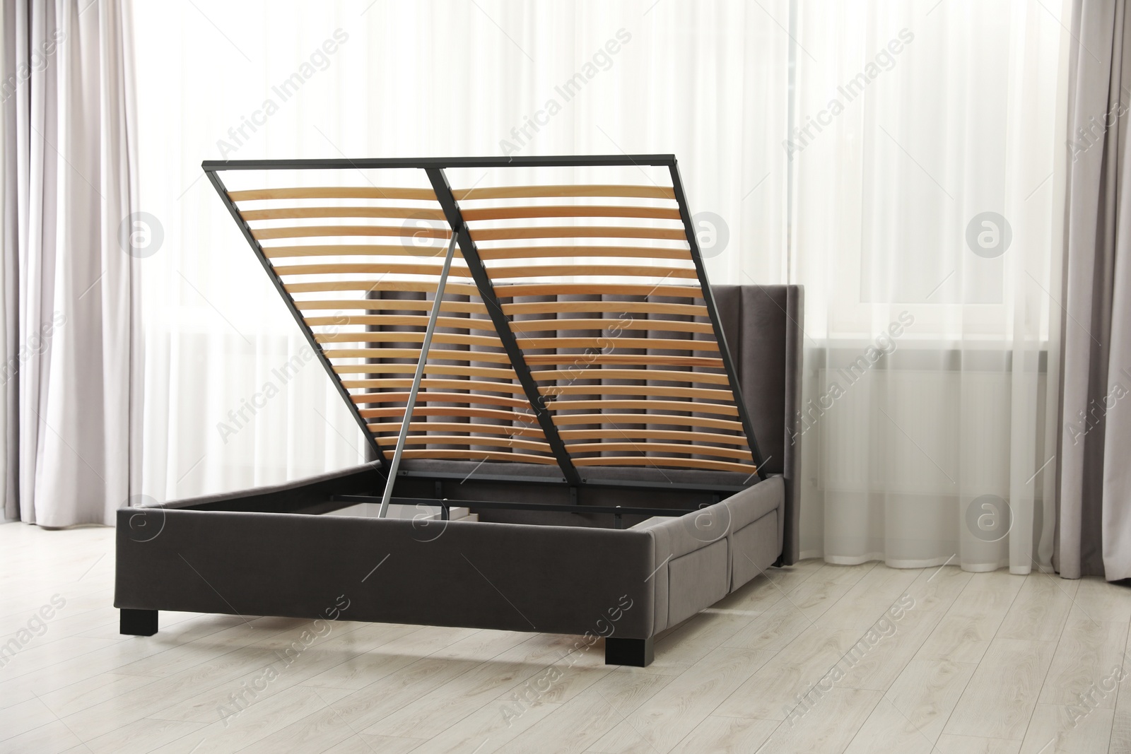 Photo of Modern bed with storage space for bedding under lifted slatted base in room