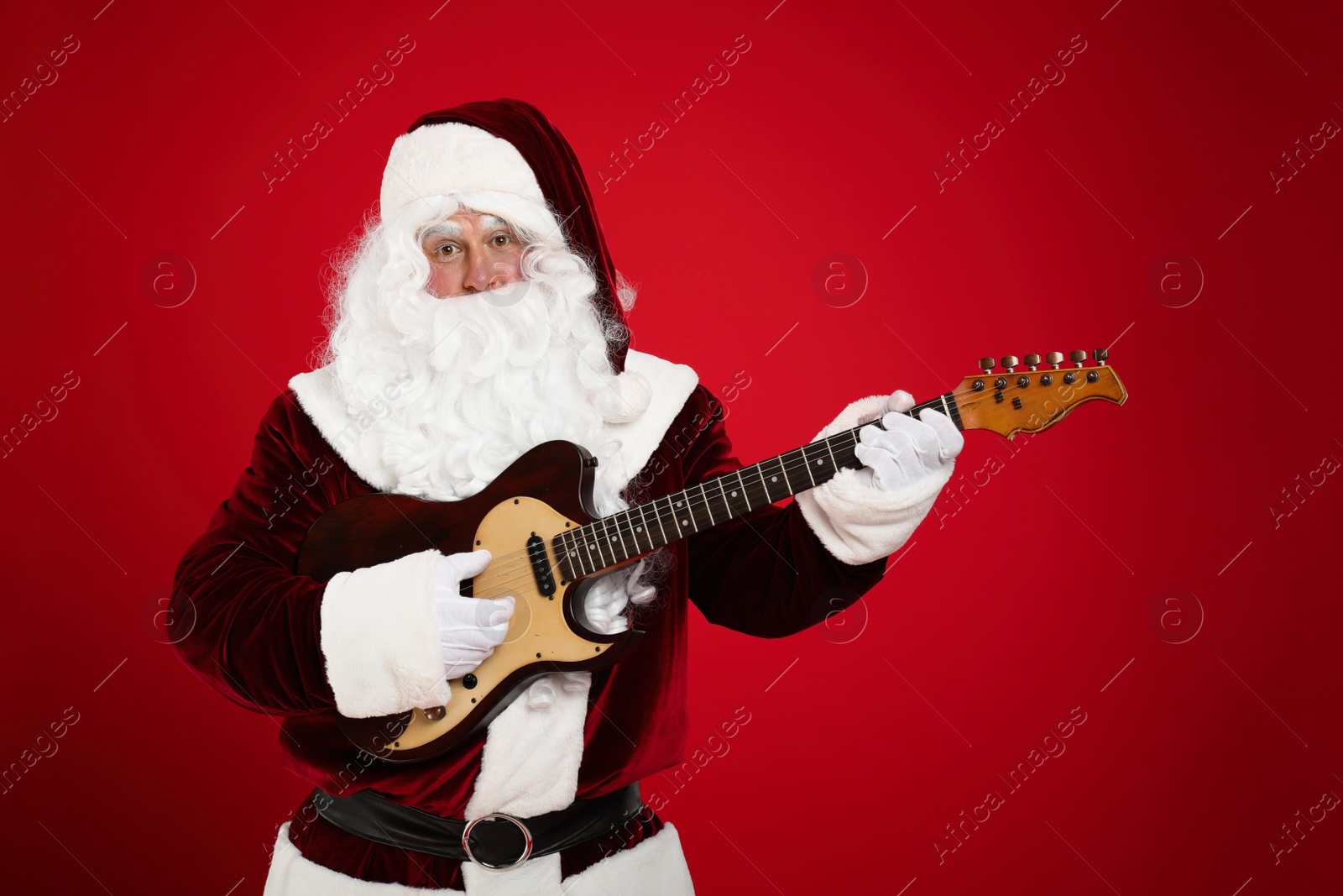 Photo of Santa Claus playing electric guitar on red background. Christmas music