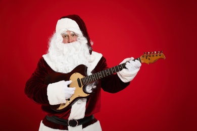 Santa Claus playing electric guitar on red background. Christmas music