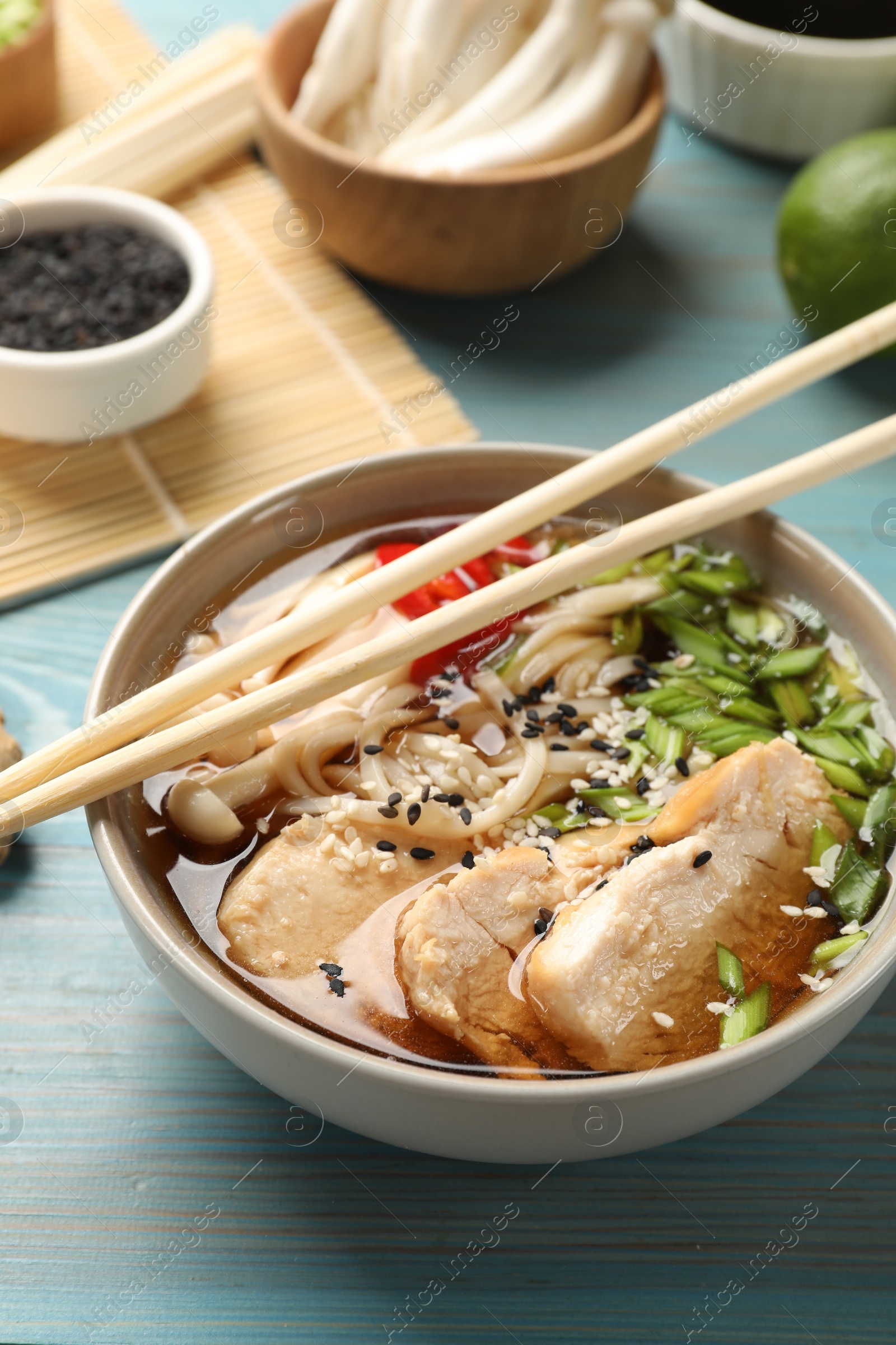 Photo of Delicious ramen with meat and ingredients on light blue wooden table. Noodle soup