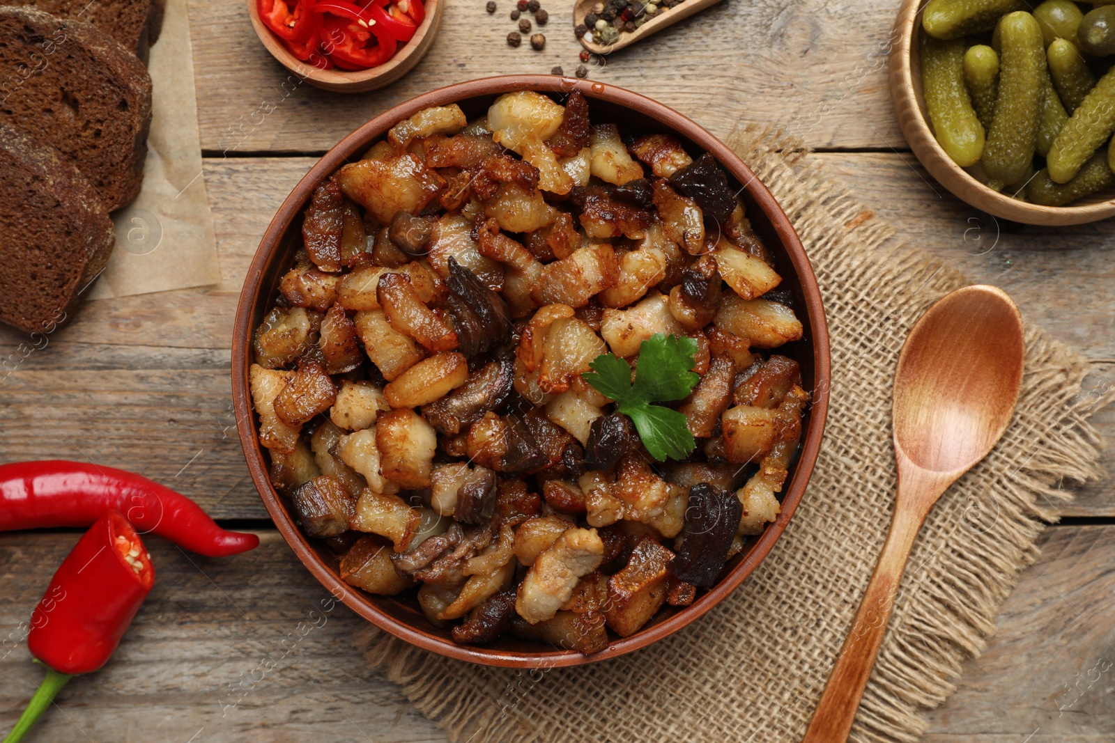 Photo of Tasty fried cracklings on wooden table, flat lay. Cooked pork lard