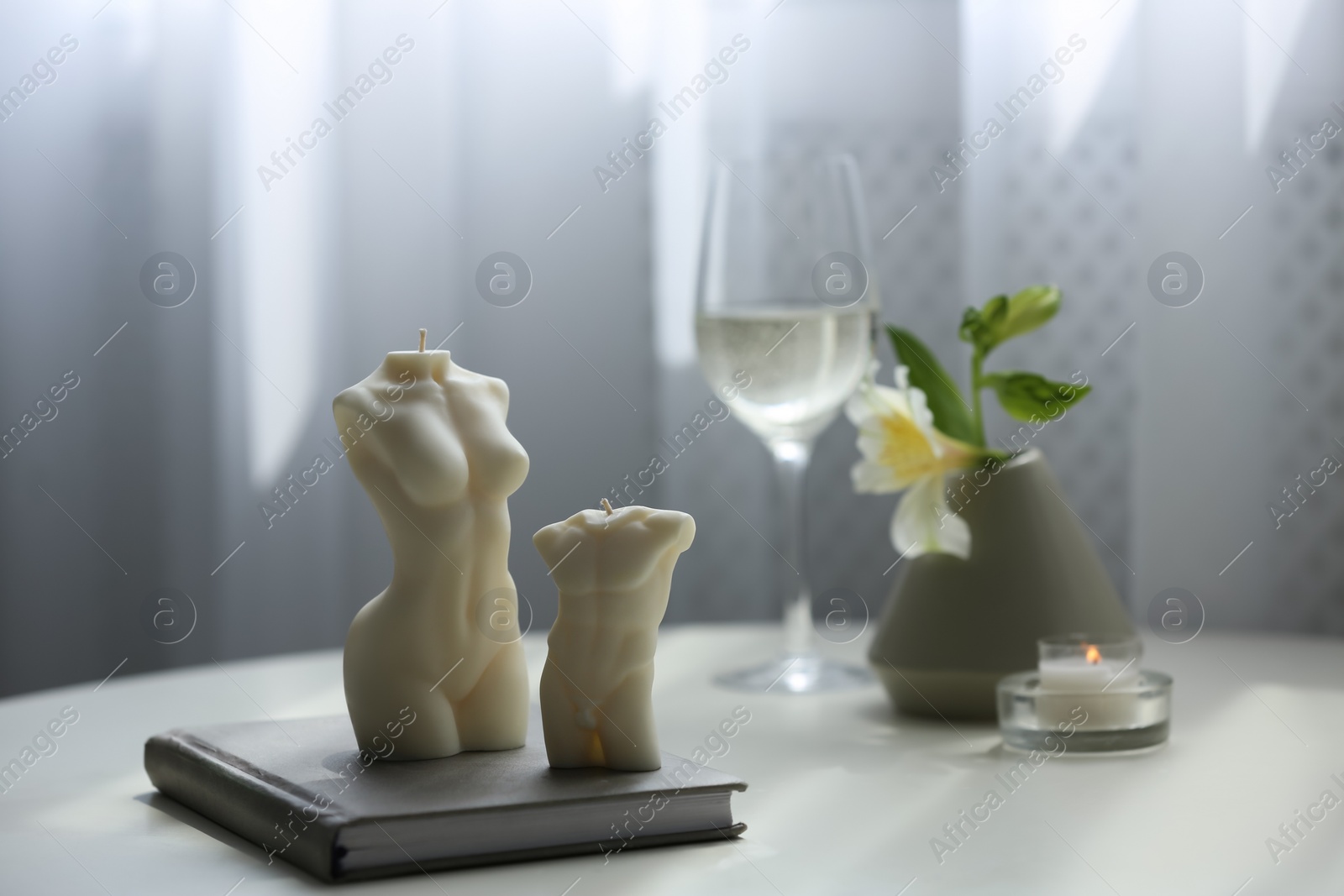 Photo of Beautiful body shaped candles and book on table indoors, space for text