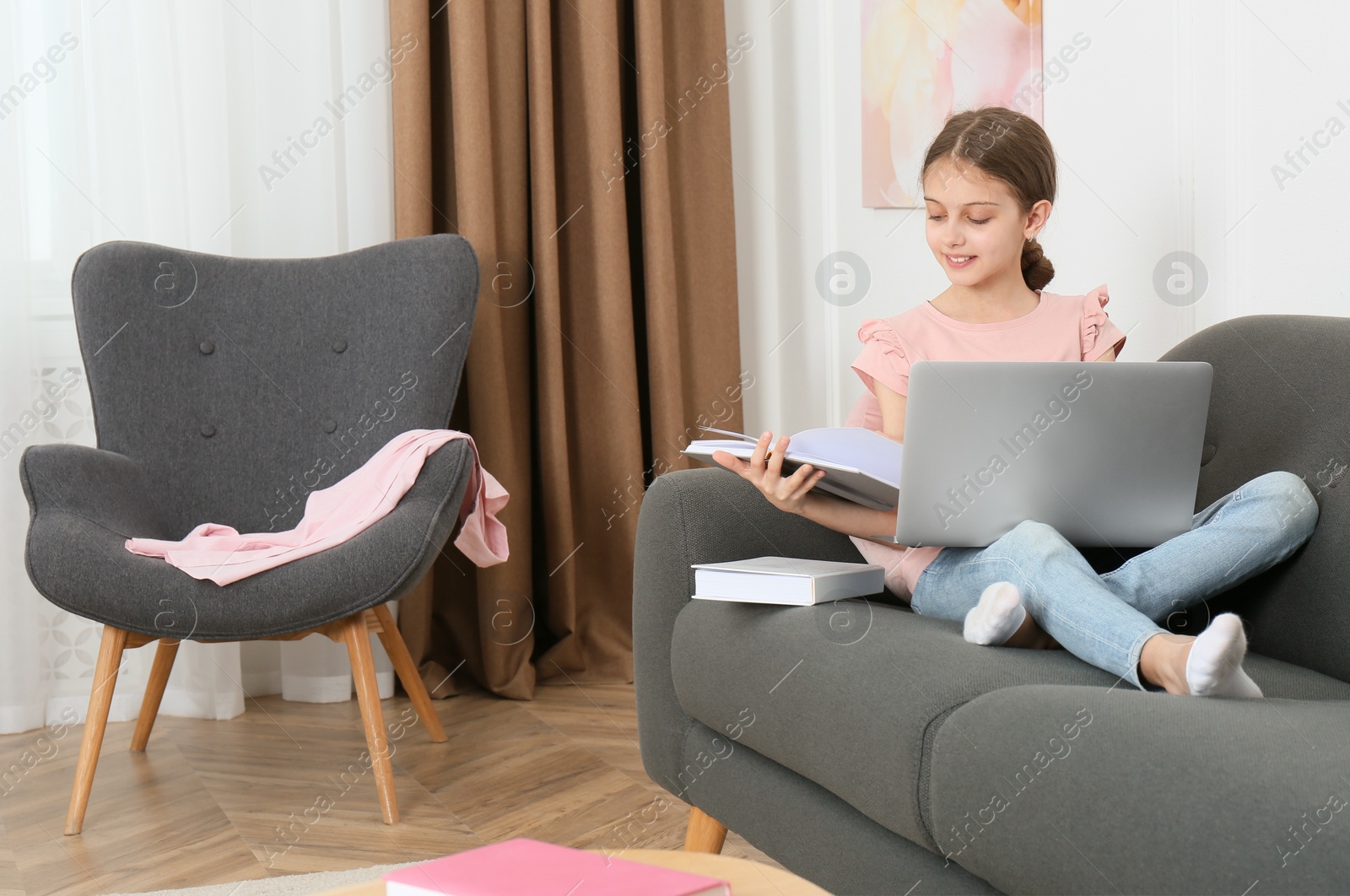 Photo of Girl with laptop and books on sofa at home