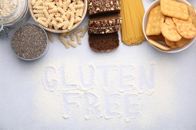 Photo of Different healthy products and phrase Gluten Free made of flour on white table, flat lay