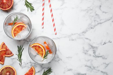 Photo of Delicious refreshing drink with sicilian orange and rosemary on white marble table, flat lay. Space for text