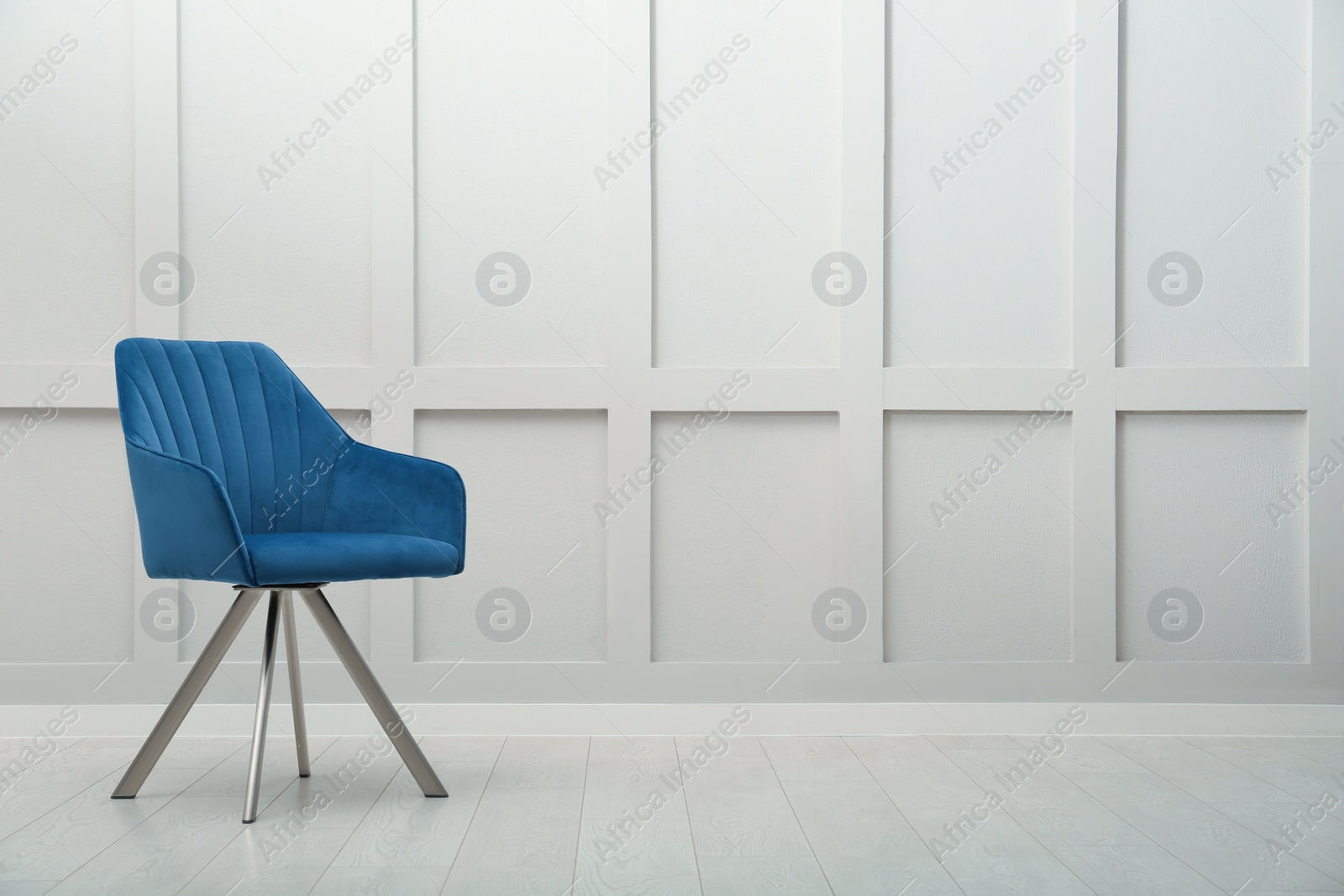 Photo of Modern blue armchair near white wall indoors. Space for text