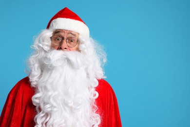 Photo of Merry Christmas. Surprised Santa Claus posing on light blue background, space for text