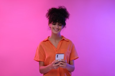 Woman sending message via smartphone on color background