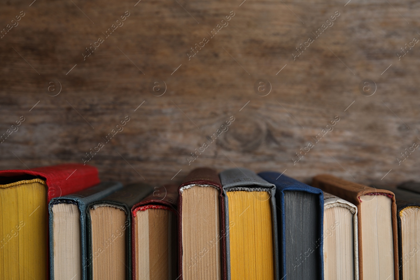 Photo of Stack of hardcover books on wooden background. Space for text