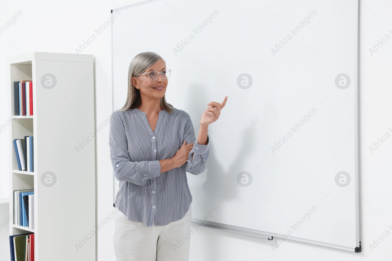 Photo of Professor giving lecture near whiteboard in classroom, space for text