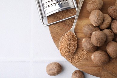 Photo of Spoon with grated nutmeg, seeds and grater on white table, flat lay. Space for text