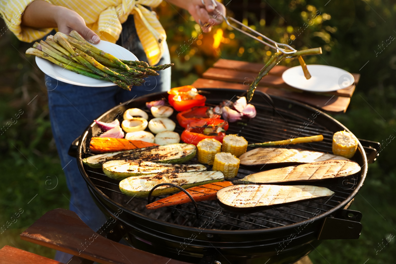 Photo of Woman cooking vegetables on barbecue grill outdoors, closeup