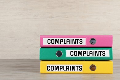 Colorful folders with Complaints labels on table, space for text