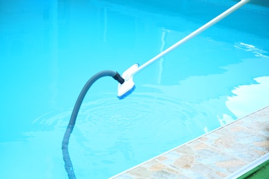 Photo of Cleaning outdoor pool with underwater vacuum, closeup