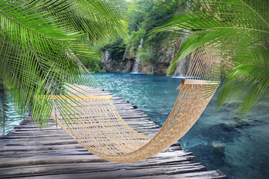 Image of Hammock between palms over wooden bridge in lake