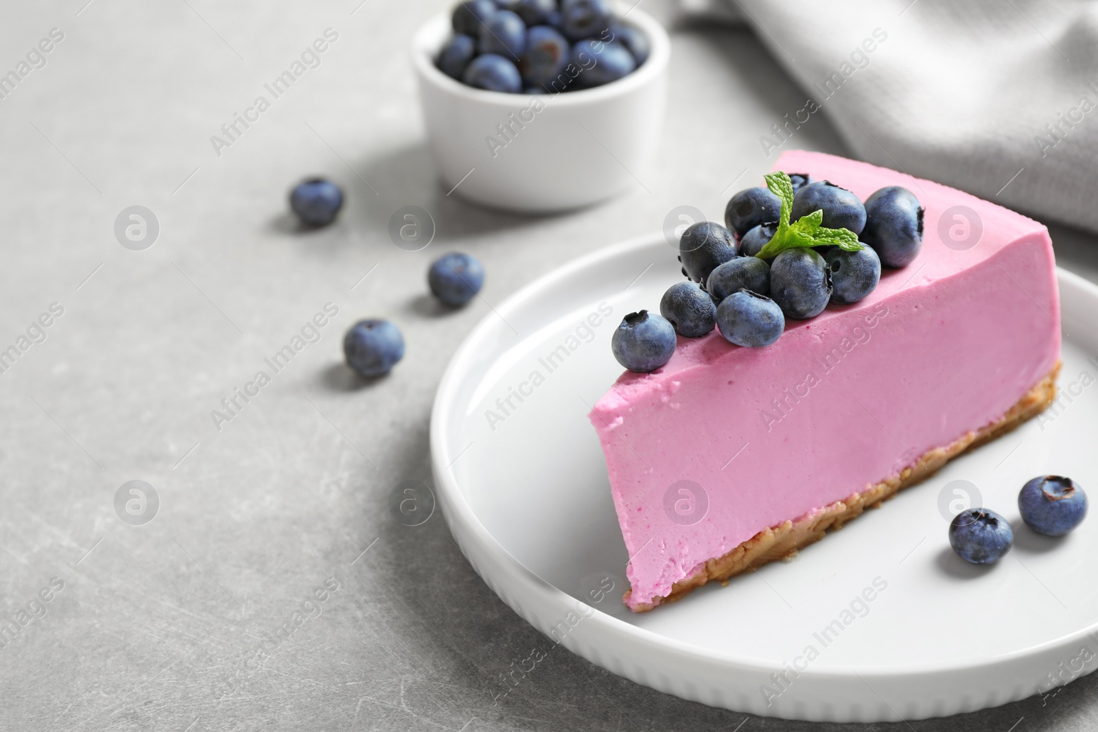 Photo of Plate with piece of tasty blueberry cake on light table. Space for text