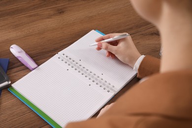 Photo of Woman taking notes at wooden table, closeup